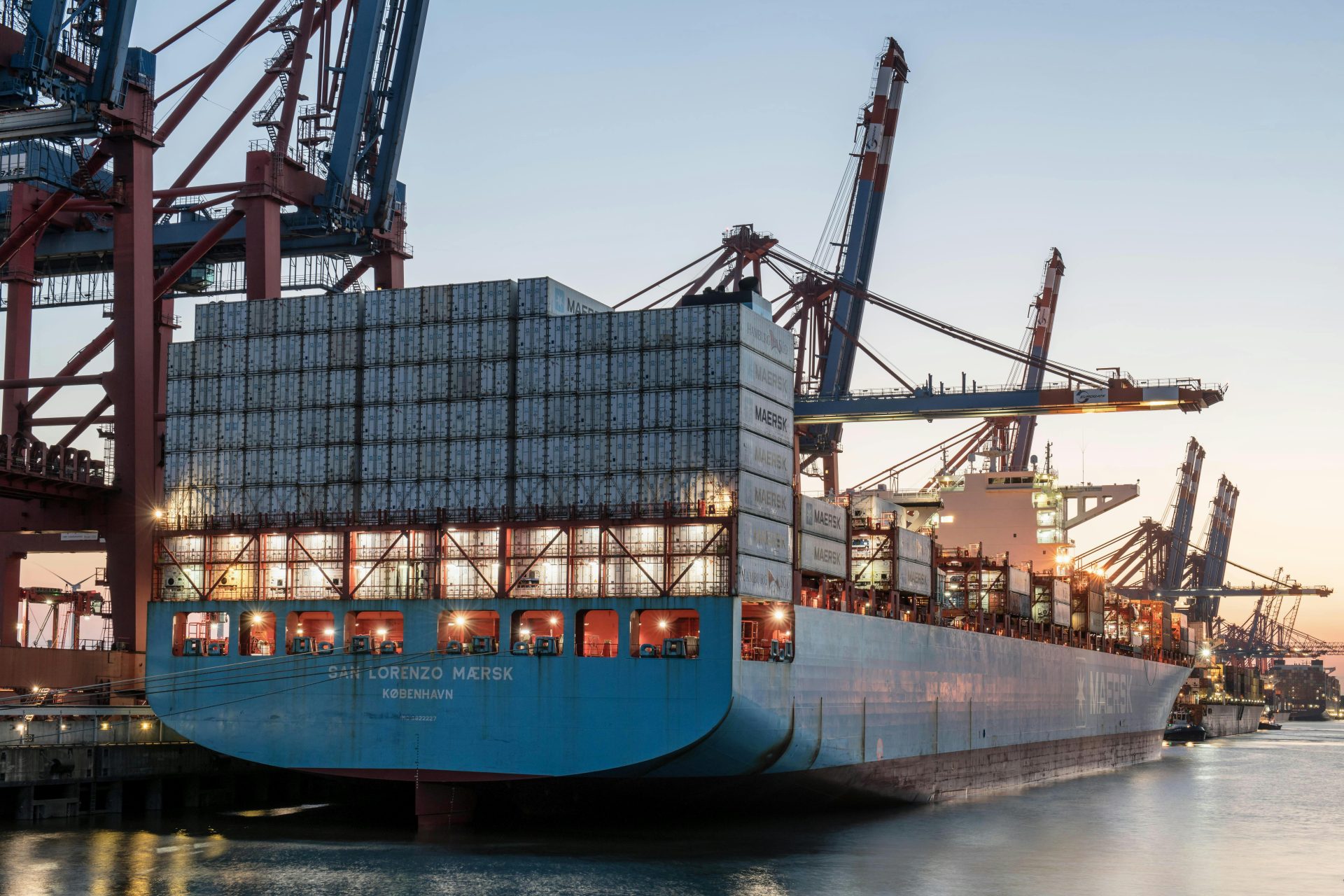 Porte-conteneurs au port de Hambourg au coucher du soleil, illustrant le commerce mondial et le transport de marchandises.